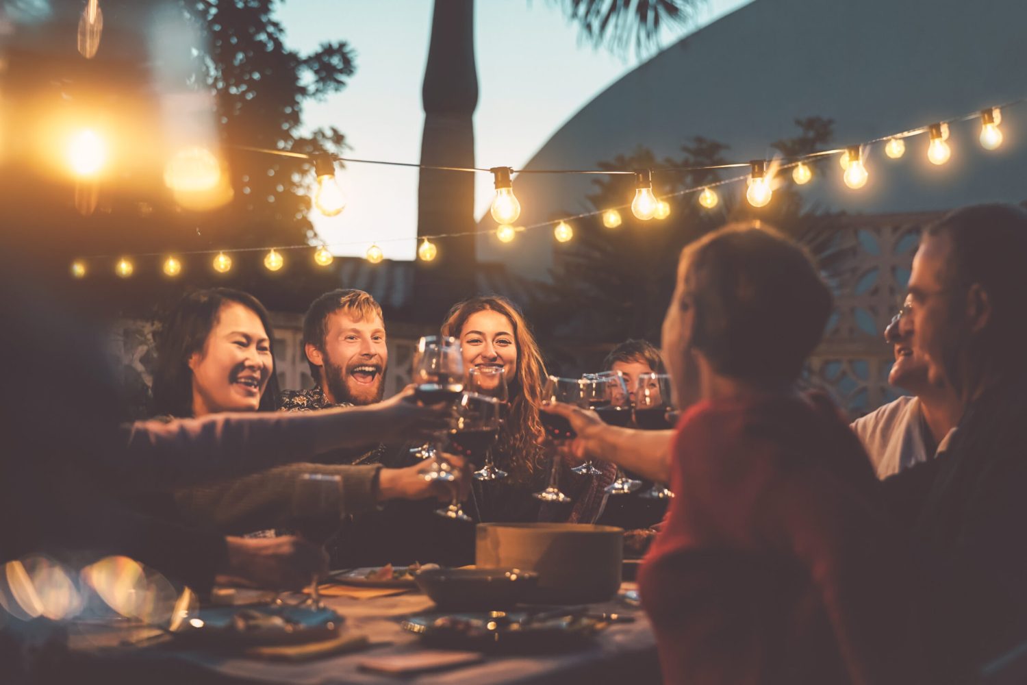 Happy family dining and tasting red wine glasses in barbecue dinner party - People with different ages and ethnicity having fun together - Youth and elderly parents and food weekend activities concept